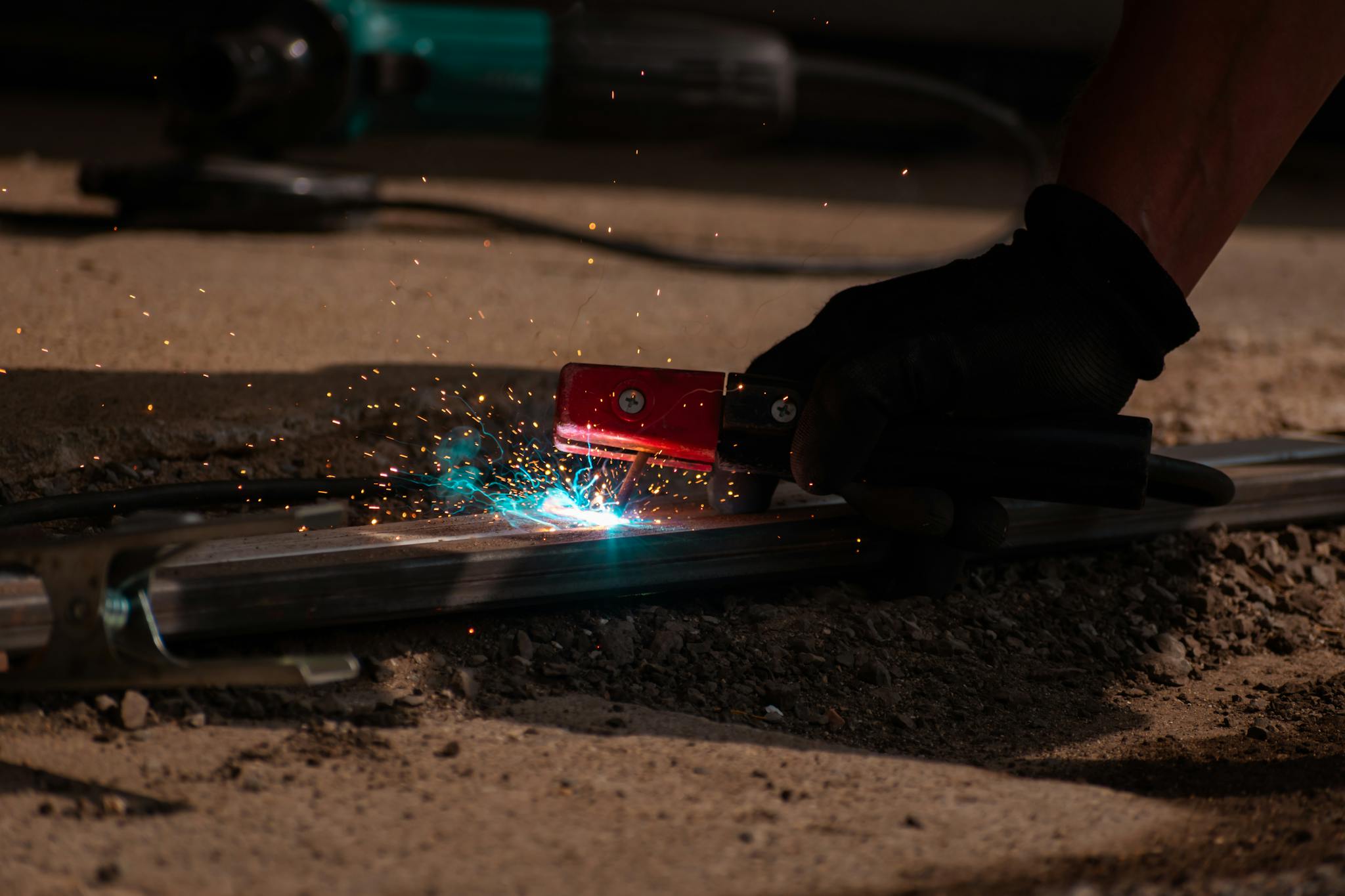 Detailed close-up of welding process with tool, sparks, and glowing metal.